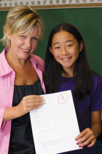 woman and young student holding up assignment with grade A